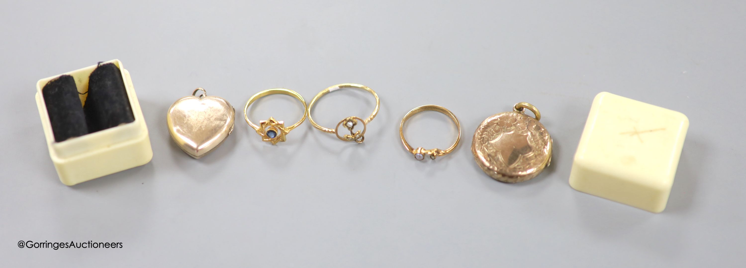 Three yellow metal and gem set rings, a yellow metal heart shaped locket and an engraved yellow metal double sided locket